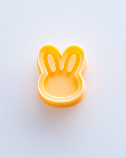 Close product view showing the printed Mini Bunny Head clay cutter beside its matching polymer clay imprint.