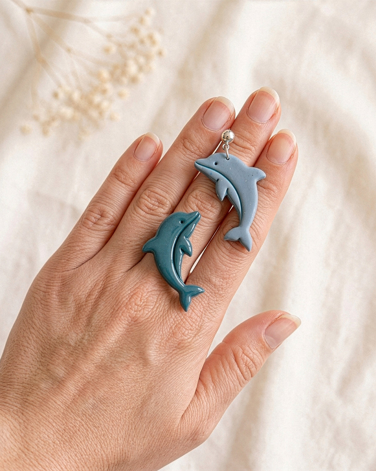 Hand-scale photograph showing the relative size of a finished Dolphin polymer clay piece.