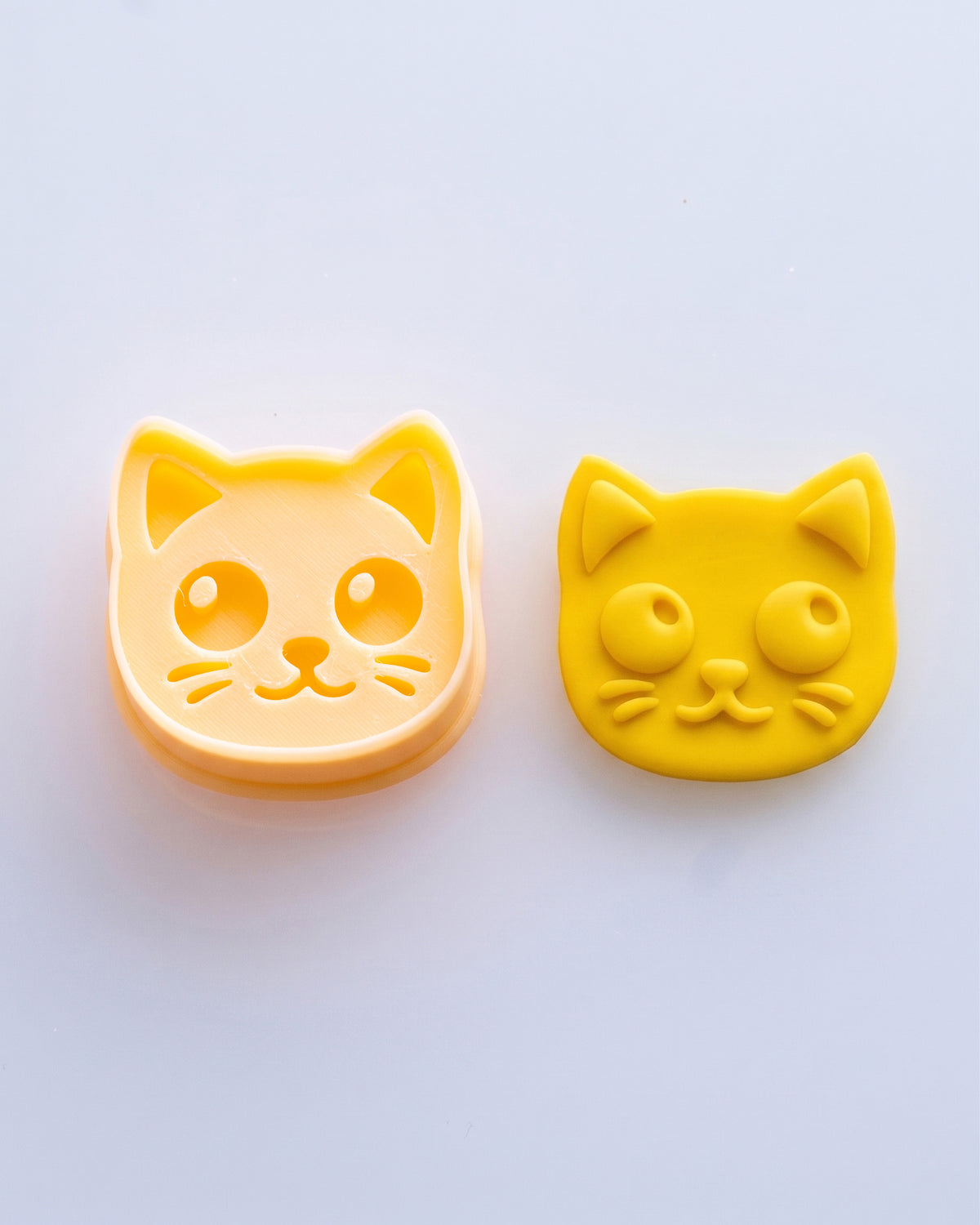 Close product view showing the printed Kitty Face clay cutter beside its matching polymer clay imprint.