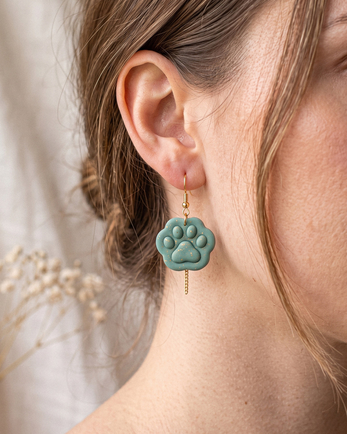 A model wearing finished Mini Paw Print polymer clay jewelry, showing its appearance and scale when worn.