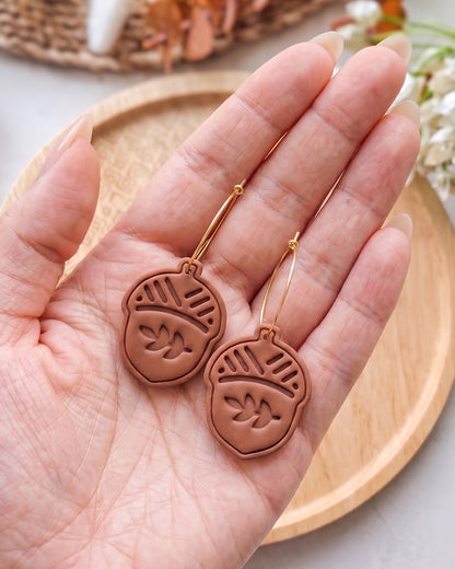 Styled lifestyle scene featuring the Oak Acorn cutter and finished polymer clay jewelry made with the design.