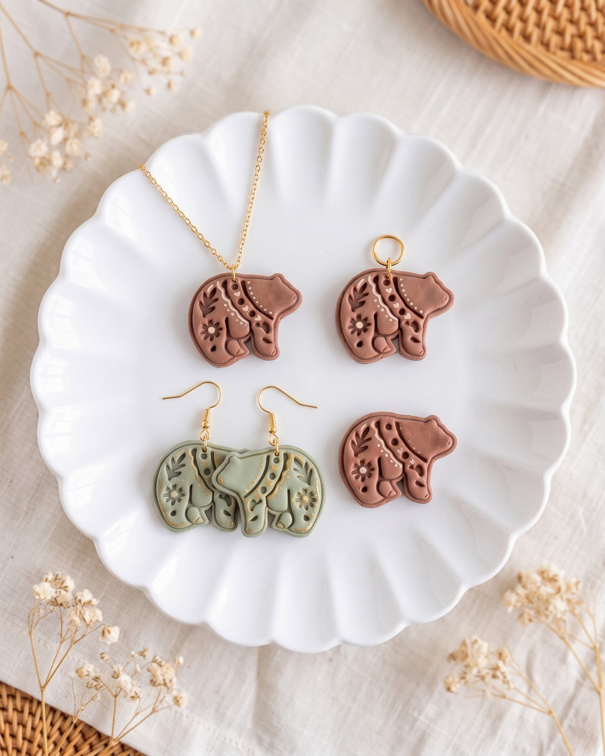 Styled lifestyle scene featuring the Scandi Folk Bear cutter and finished polymer clay jewelry made with the design.