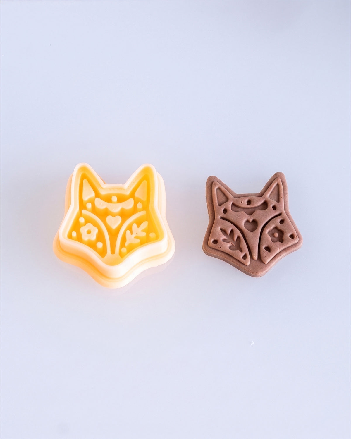 Close product view showing the printed Scandi Folk Fox Head clay cutter beside its matching polymer clay imprint.