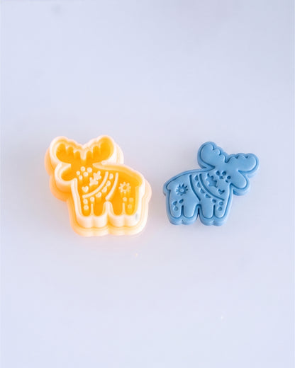 Close product view showing the printed Scandi Folk Moose clay cutter beside its matching polymer clay imprint.