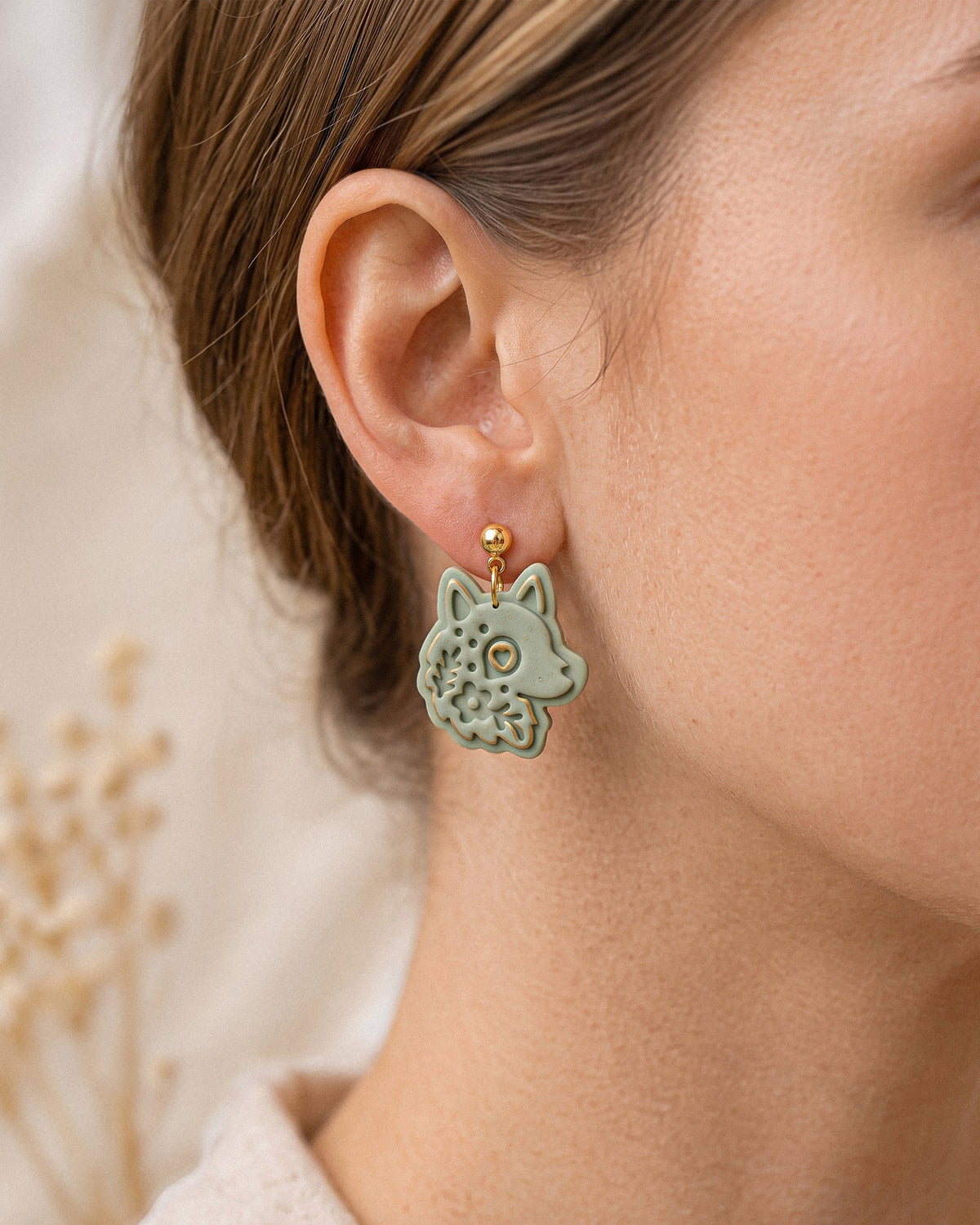 A model wearing finished Scandi Folk Wolf Head polymer clay jewelry, showing its appearance and scale when worn.