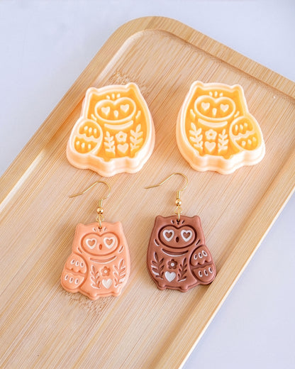 Styled lifestyle scene featuring the Scandi Owl cutter and finished polymer clay jewelry made with the design.